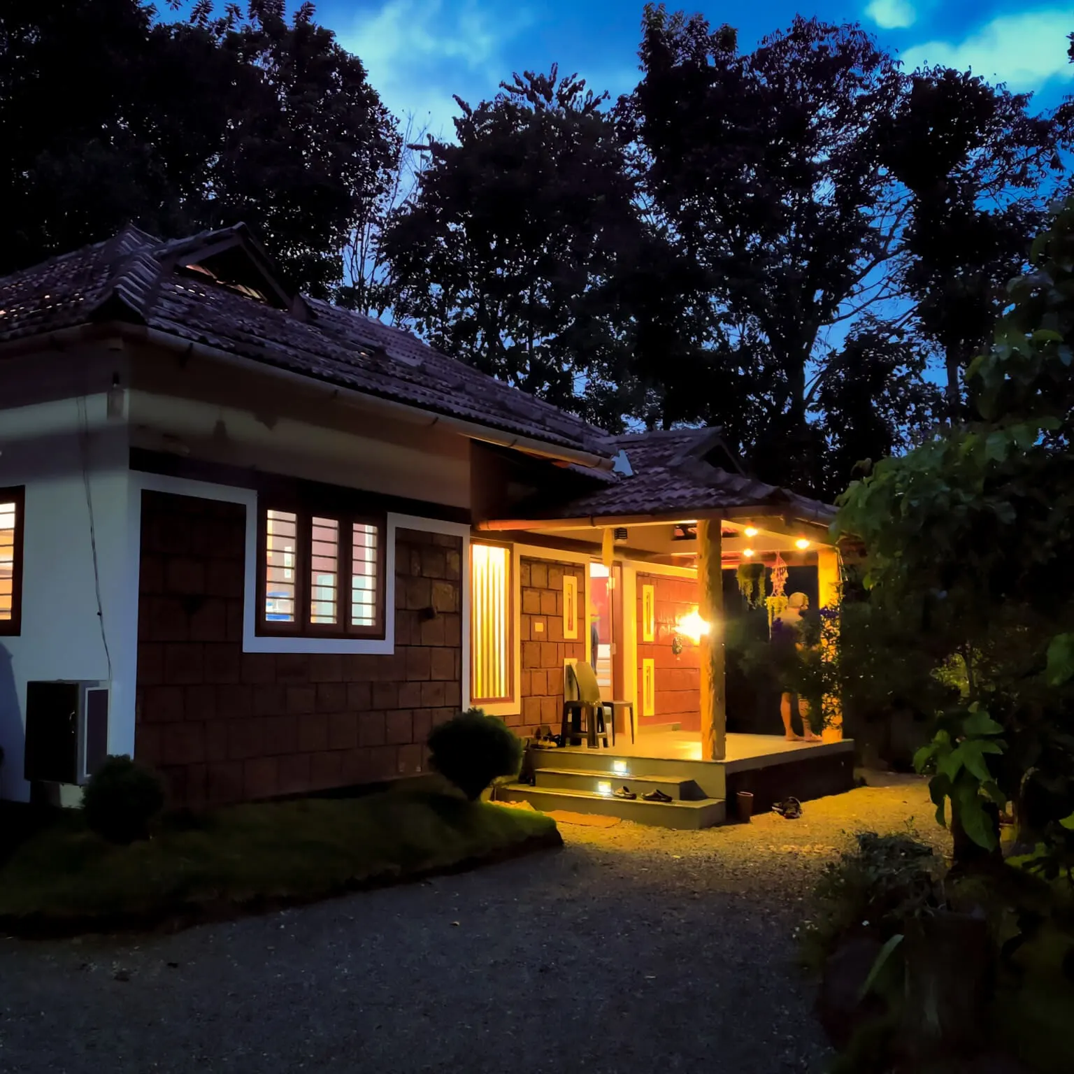 The homestay at dusk, its veranda and porch lights lit
