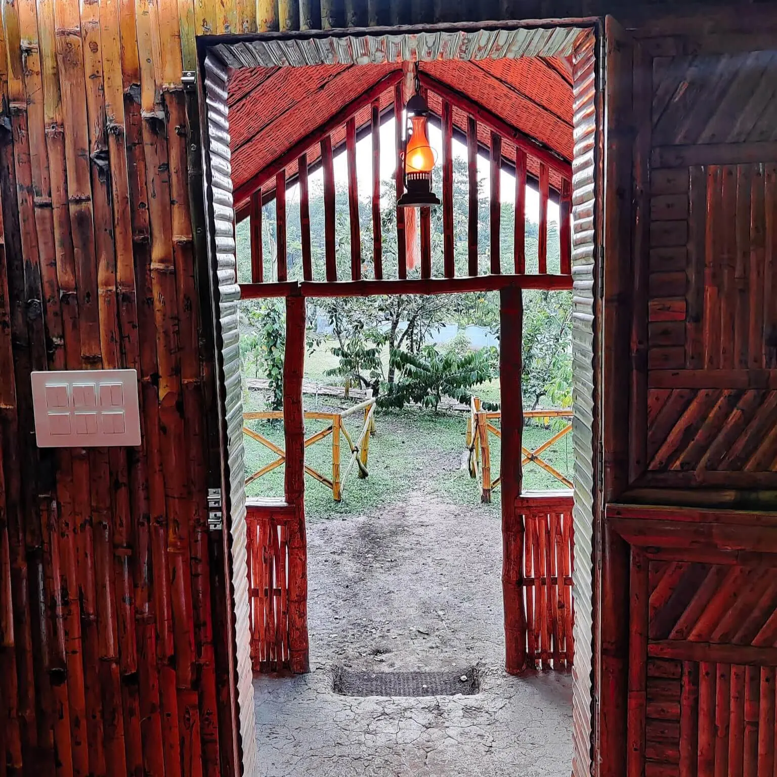 The view out through a wooden doorway to a railed porch and the garden