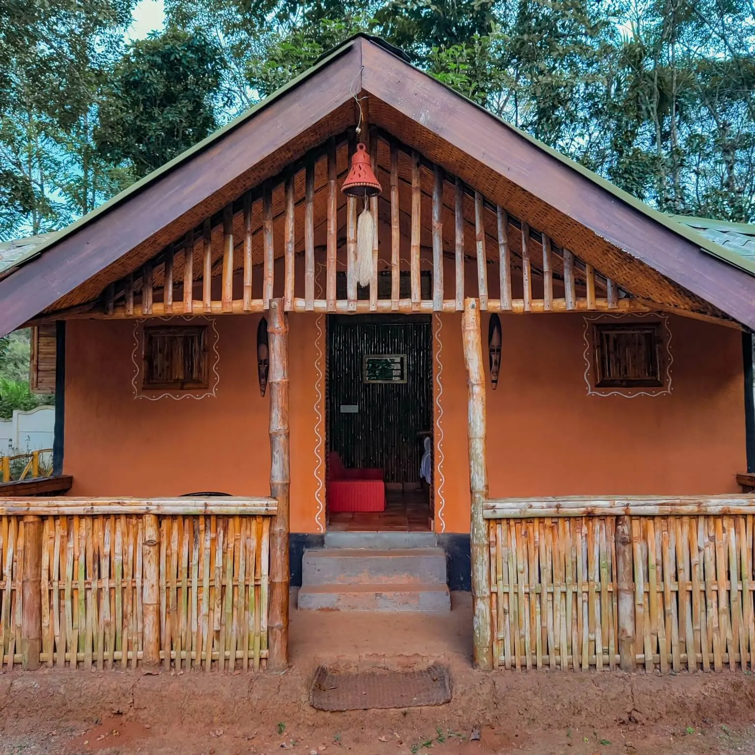 The bamboo-fronted hut at Juvi Dacha, with a railed veranda and steps up to the door