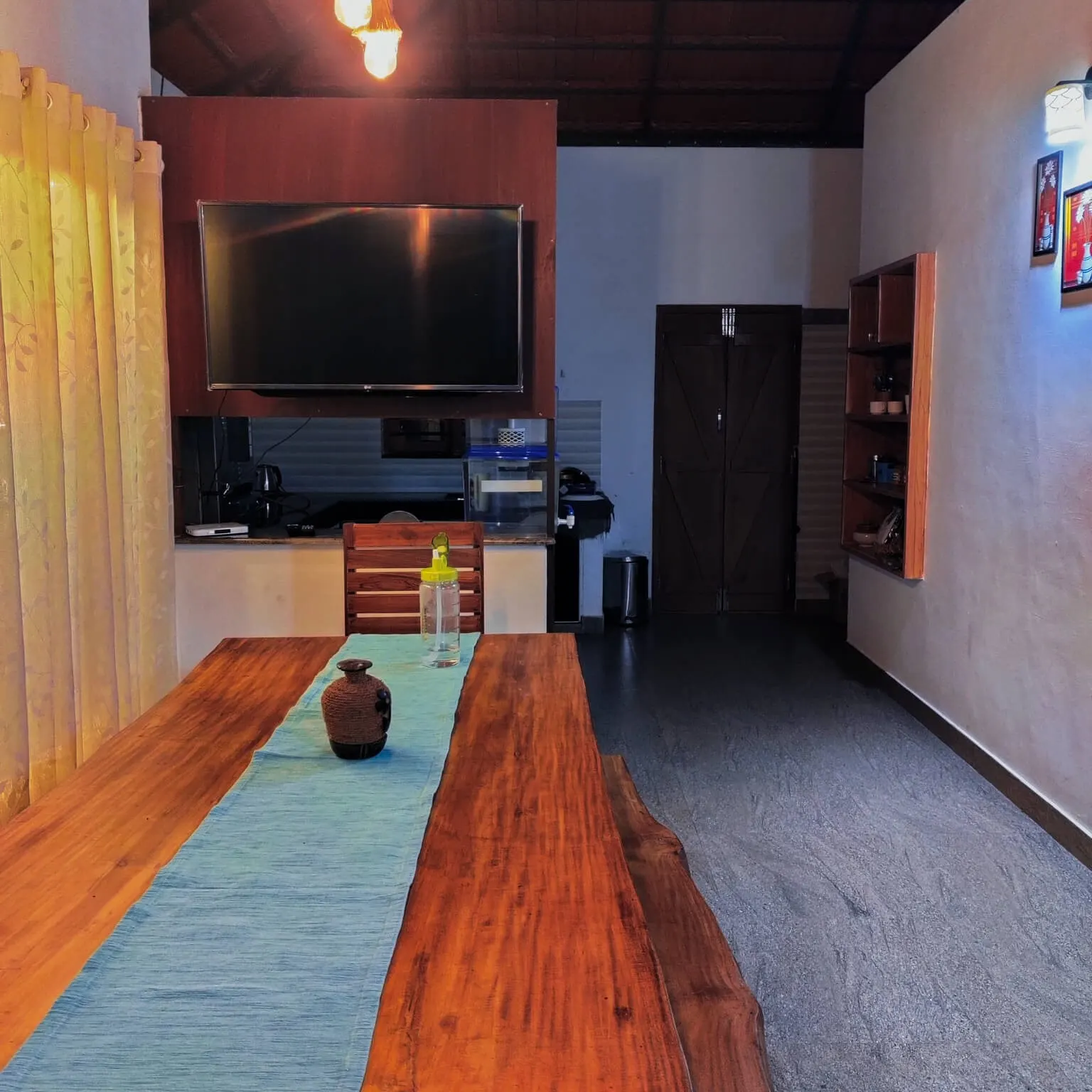 The living and dining area in Agate villa, with a long wooden table and a wall-mounted television