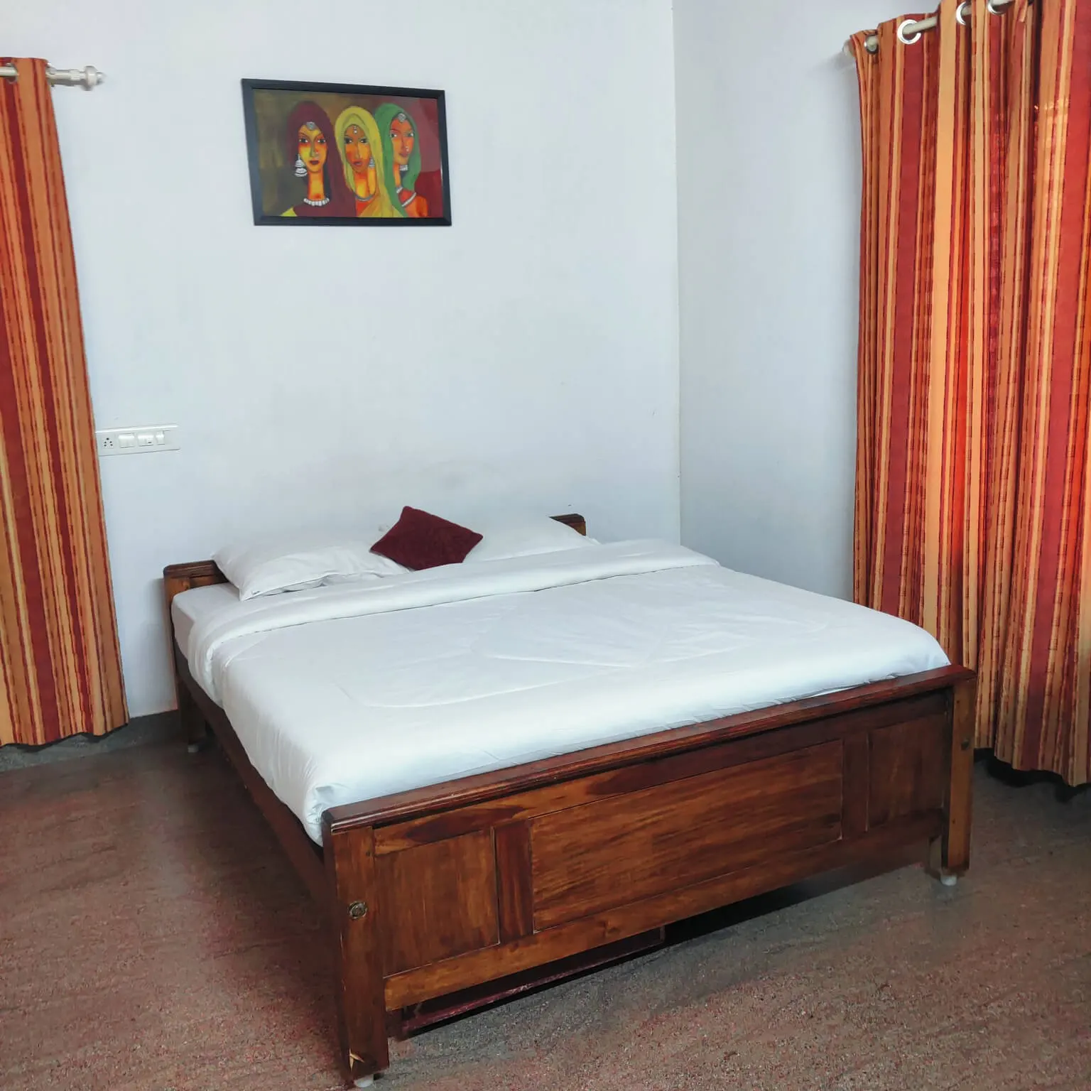 A double bedroom in Agate villa, with striped curtains and a framed picture above the bed