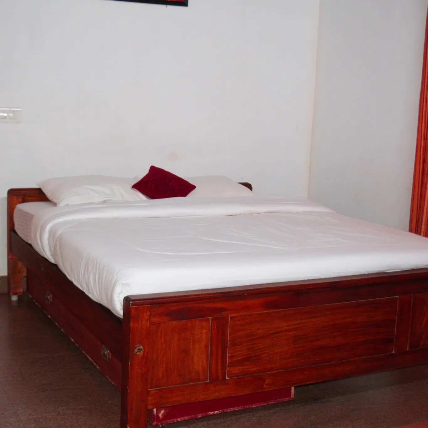 The bedroom in Beryl, the single-room cottage, with a wooden double bed against a white wall